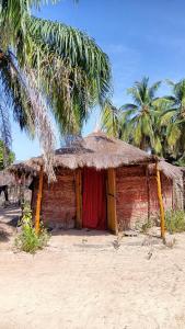 un petit bâtiment en briques avec un toit de paille dans l'établissement Campement Kaymba Lodge, à Kachiouane