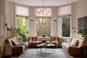 a living room with leather furniture and windows at Sonder Park House in Amsterdam