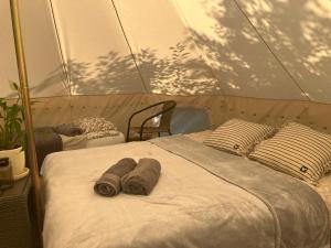 a bed with two rolled towels on it in a tent at Mazury Glamping Kruklanki Polana Życzeń in Kruklanki