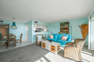 ein Wohnzimmer mit einem blauen Sofa und Stühlen in der Unterkunft Sunset Terrace 104 in Bradenton Beach