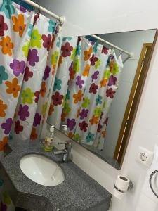 a bathroom with a sink and a shower curtain at Suite Big Lanche in Praia Baixo