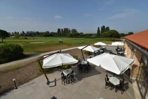 - une vue sur la terrasse dotée de tables et de parasols blancs dans l'établissement Jesolo Living at Golf Club Jesolo, à Jesolo