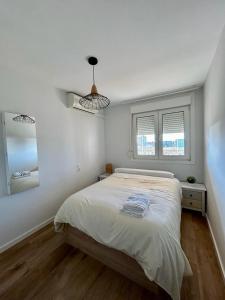 a white bedroom with a bed and two windows at Apartamento Benicàssim Sunset Calm&Views in Benicàssim