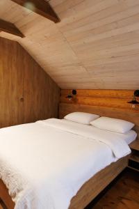 Schlafzimmer mit einem großen weißen Bett und Holzwänden in der Unterkunft Wild River in Neporotovo