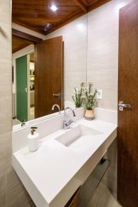 La salle de bains est pourvue d'un lavabo blanc et d'un miroir. dans l'établissement Pousada Village Feliz Boipeba, à Île de Boipeba