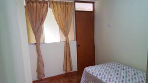 Schlafzimmer mit einem Fenster mit Vorhängen und einem Bett in der Unterkunft Hospedaje Arana in Chincha Alta