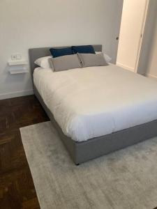 Apartamento elegante céntrico في فيغو: غرفة نوم بسرير كبير مع شراشف بيضاء ومخدات زرقاء
