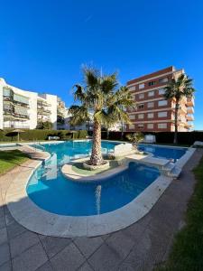 a swimming pool with a palm tree and buildings at Apartamento Benicàssim Sunset Calm&Views in Benicàssim