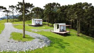 dos pequeñas estructuras en un campo de césped con árboles en Cápsula futurística - Experiência única. en Urubici