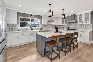 a kitchen with white cabinets and a island with bar chairs at Huntington Beach, AC, Pool, Hot Tub, Detached Office, Close to Beach, Outside Entertaining Area in Huntington Beach