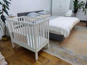 1 dormitorio con cuna y 1 cama con alfombra en Allomas Apartman, en Budapest