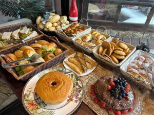 una mesa con muchas bandejas de diferentes tipos de pan y repostería en Pousada Solar de Búzios, en Búzios