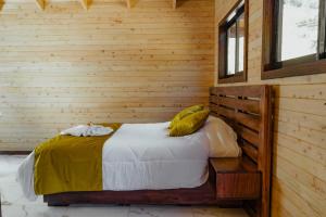 1 dormitorio con 1 cama en una pared de madera en Cabinas El Quetzal, en San Gerardo de Dota