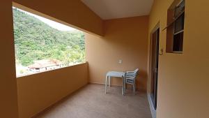 a room with a table and chairs and a window at Pousada Alejandro in Cunha
