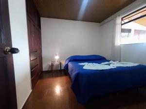 ein Schlafzimmer mit einem blauen Bett und einem Fenster in der Unterkunft Apartamentos Casa MJ Tunja in Tunja