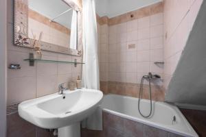 a bathroom with a sink and a bath tub at Pefkohori Blue View by Luxlikehome in Pefkochori +25 photos