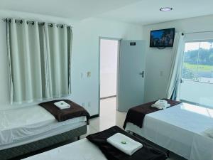 a bedroom with two beds and a large window at Hotel Colorado in Eunápolis