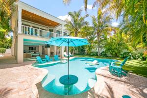 a pool with a blue umbrella and chairs and a house at Southern Exposure AMV in Anna Maria