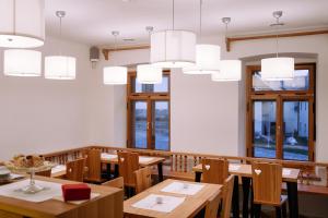 un ristorante con tavoli e sedie in legno e lampadari a braccio di Pr'Gavedarjo Eco Heritage B&B a Kranjska Gora