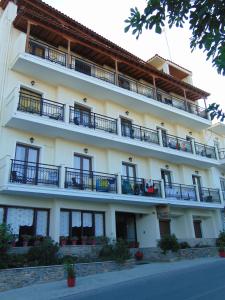 a large white building with balconies and a street at Xanemos Port in Skiathos