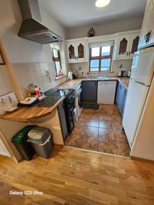 a kitchen with white appliances and a wooden floor at Roadside Cottage The Burren in Kilfenora
