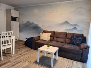 een woonkamer met een bank en een muurschildering van de bergen bij Apartmán Pod Mamutem in Dolní Morava