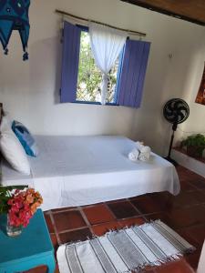 a bedroom with a white bed with a window at Chalé Flor do Ser in Canoa Quebrada