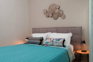 a bed with a blue comforter and some pillows at Virginia's Luxury Suites 2 in Volos