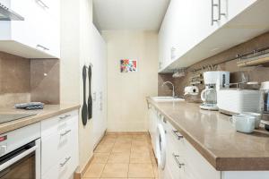 una cocina con armarios blancos y electrodomésticos blancos en Intercontinental Superbe appartement avec piscine en Menton
