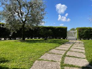 un camino de piedra en un campo con una valla y un árbol en Il Fienile di Manerba, en Manerba del Garda