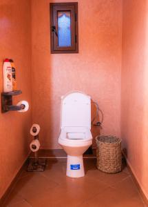 a bathroom with a toilet with a window and a basket at Riad Rihana Dades in Boumalne