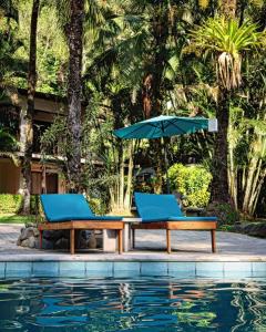 twee stoelen en een parasol naast een zwembad bij Rio Lindo Hotel in Dominical