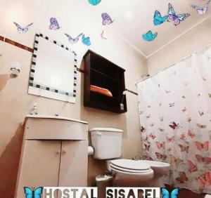 a bathroom with a toilet and butterflies on the wall at Hostal Sisabel in Tinogasta