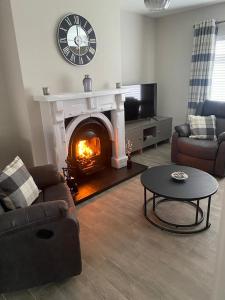 a living room with a fireplace with a clock on the wall at Drumnieve Lodge in Kesh