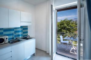 a kitchen with white cabinets and a balcony with a table at SorrentoVibes - Deluxe Apartment in Sorrento Centre in Sorrento +11 photos