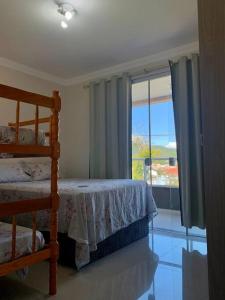 een slaapkamer met een bed en een raam met uitzicht bij Apartamento Novo em Bombinhas a 300 mt da praia Bombas in Bombinhas