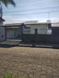 une maison avec une clôture devant elle dans l'établissement Casa próximo a praia com churrasqueira e ar condicionado!, à Caraguatatuba