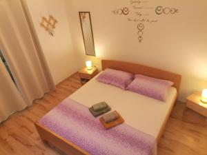 1 dormitorio con 1 cama con sábanas moradas y espejo en Apartments Green & Orange, en Hvar