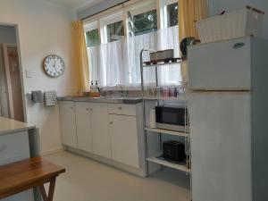 a kitchen with a refrigerator and a clock on the wall at La Petite Ferme Studio Kerikeri in Kerikeri