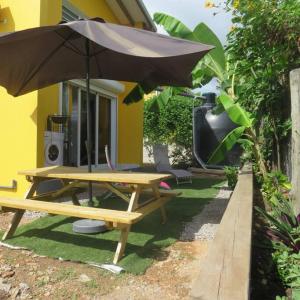 a picnic table with an umbrella in front of a house at Jeune Tournesol (Bungalow neuf) in Sainte-Anne