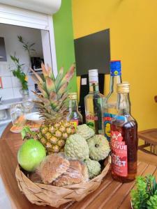 a table with a basket of fruit and bottles of alcohol at Jeune Tournesol (Bungalow neuf) in Sainte-Anne