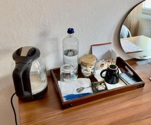 - un plateau en bois avec une bouteille d'eau et un miroir dans l'établissement Convini Bed & Bathroom Homestay, à Pristina