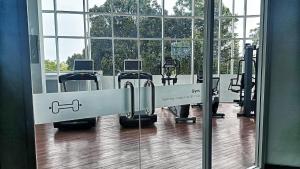 un gimnasio con cintas de correr y máquinas en una habitación con ventanas en SLEPTOPIA at THE NOVE NONGSA COZY HOOK PREMIUM UNIT WITH AMAZING VIEW, en Nongsa