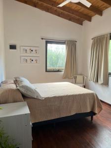 een slaapkamer met een groot bed en een raam bij Algarrobos del Mirador in Santa Rosa de Calamuchita