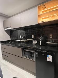 カベデロにあるFLAT aconchegante e moderno, 100m do marのシンクと電子レンジ付きのキッチン
