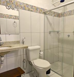 a bathroom with a toilet and a glass shower at Villa Mar a Vista - Suite Alamanda in Cumuruxatiba