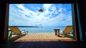 two chairs and a table on a dock with the ocean at The Sea Monkey in Bocas del Toro