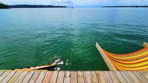 a hammock sitting on a dock next to the water at The Sea Monkey in Bocas del Toro