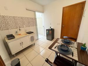 a kitchen with a table and a sink and a refrigerator at Kitnet no coração de Serra Negra in Serra Negra