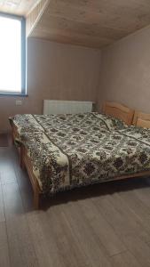 a bedroom with a bed with a comforter on it at saxli tyis piras in Bakuriani